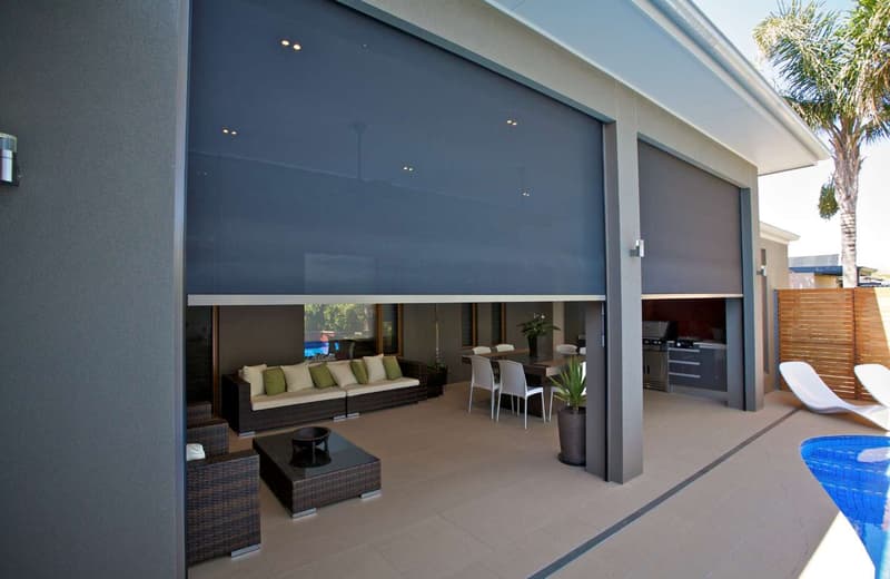 Outdoor blinds lowered across an alfresco area beside a lawn