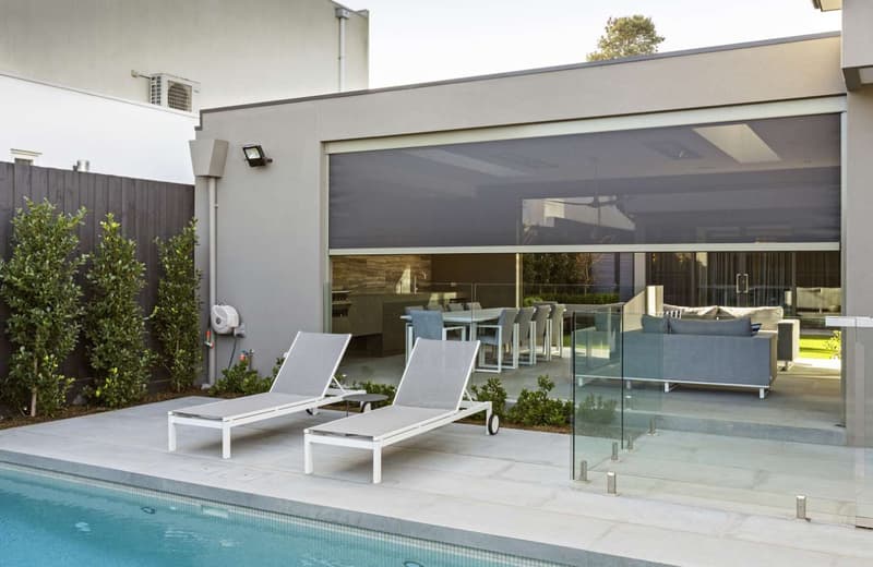 Outdoor blind lowered over a poolside entertaining area