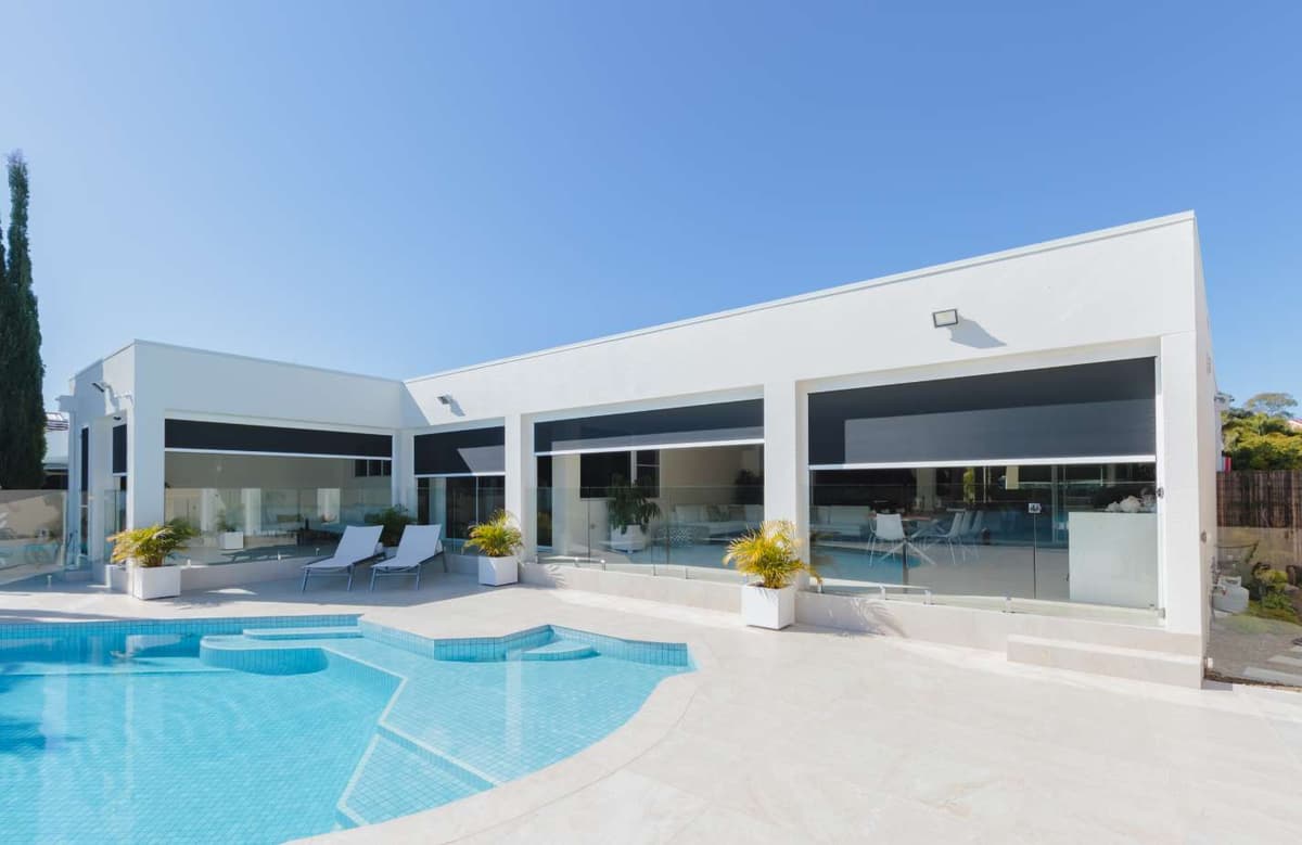 Motorised outdoor blinds fitted across a poolside patio on a white Gold Coast home
