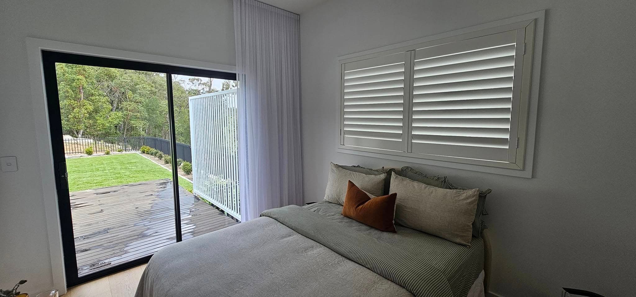 Plantation shutters in a Gold Coast bedroom opening onto a timber deck
