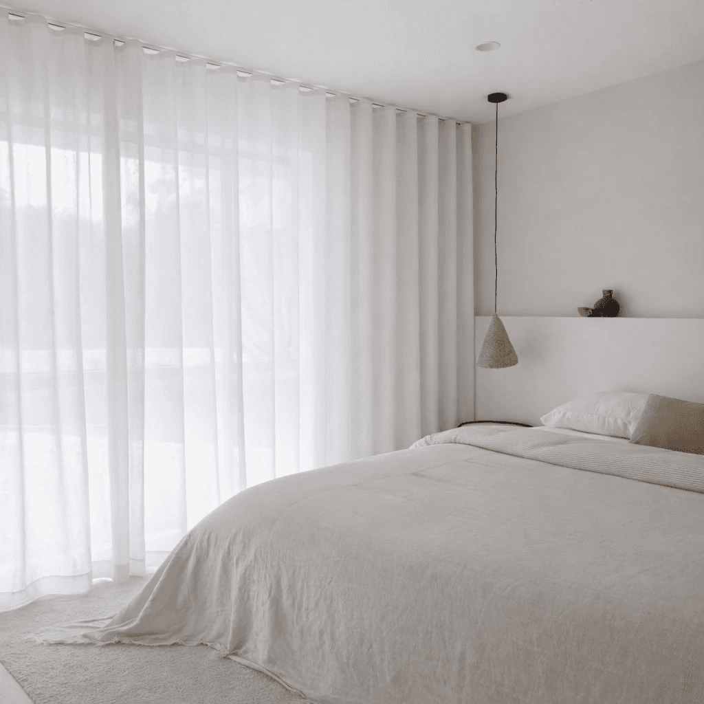 Wave fold sheer curtains hanging in continuous S-fold waves across a bedroom window wall